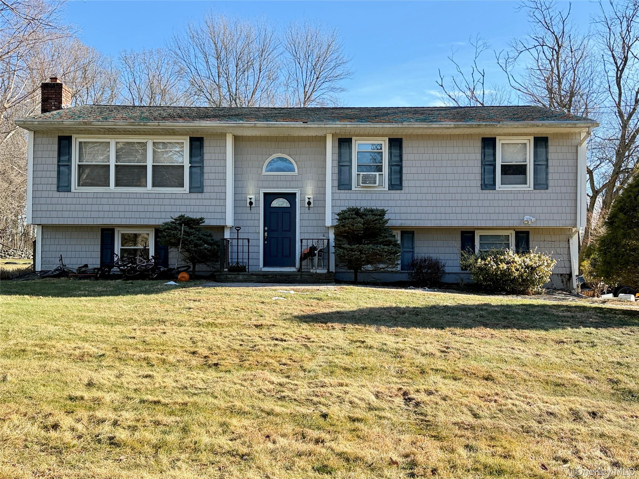 Bi-level home featuring a front lawn and a chimney
