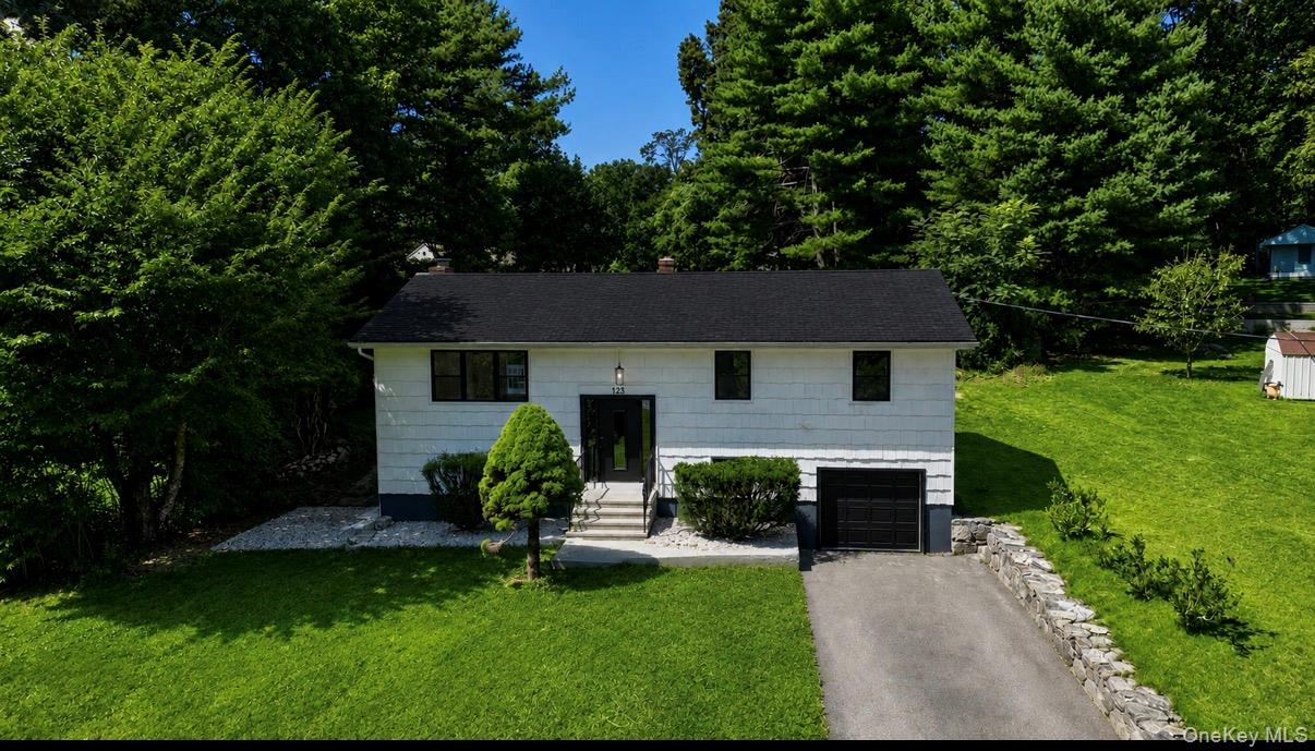 White siding exterior with a dark shingle roof, integrated garage, and concrete driveway