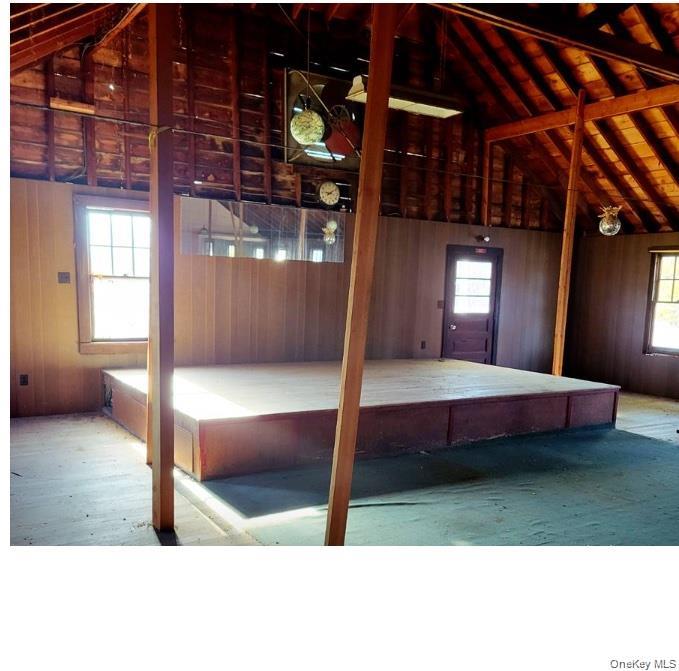 Misc room featuring lofted ceiling, wood walls, and a garage.
