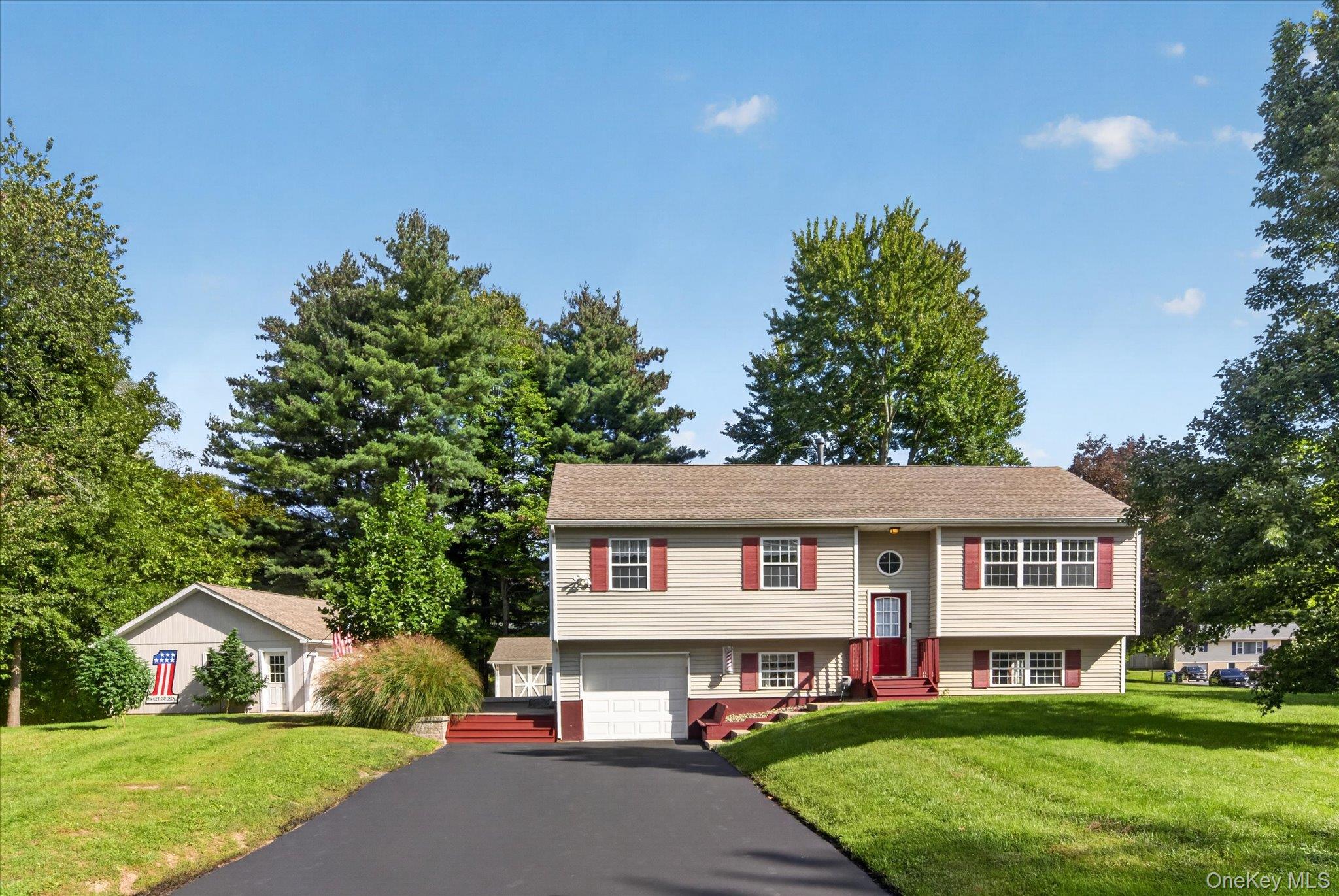 Split-level residence featuring a two-car garage, red entry door, and red window shutters