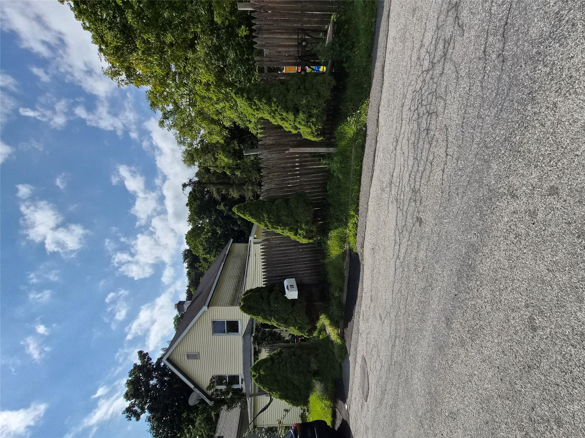 Front of home lined with wooden fence and evergreens.