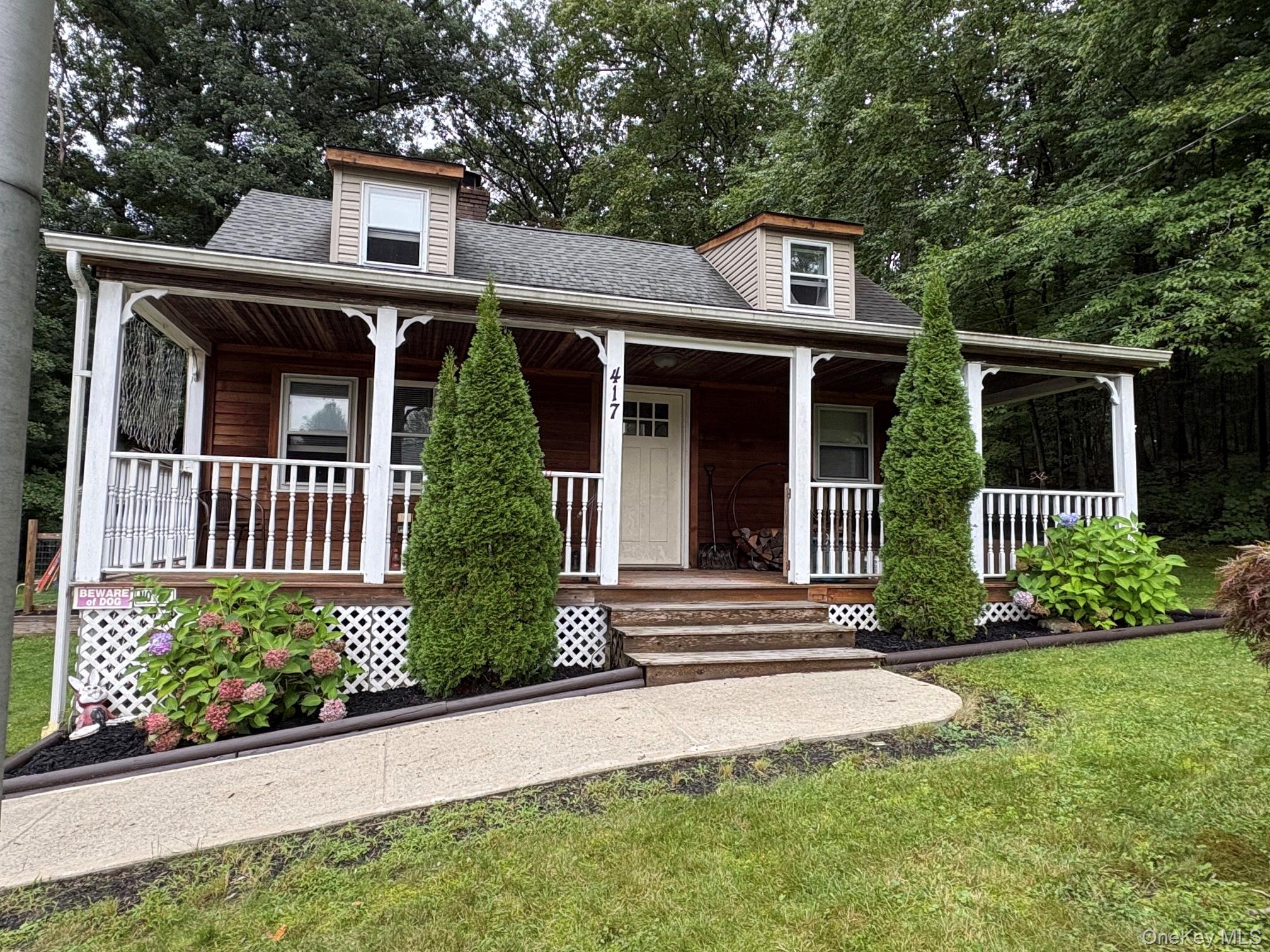 Wood-sided exterior featuring dormer windows and a covered front porch with white railings