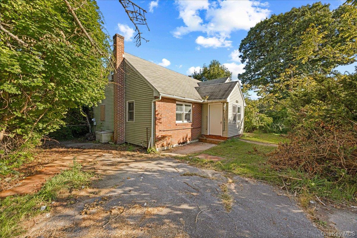 House exterior featuring brick and siding finishes, a prominent brick chimney, and a gabled roofline