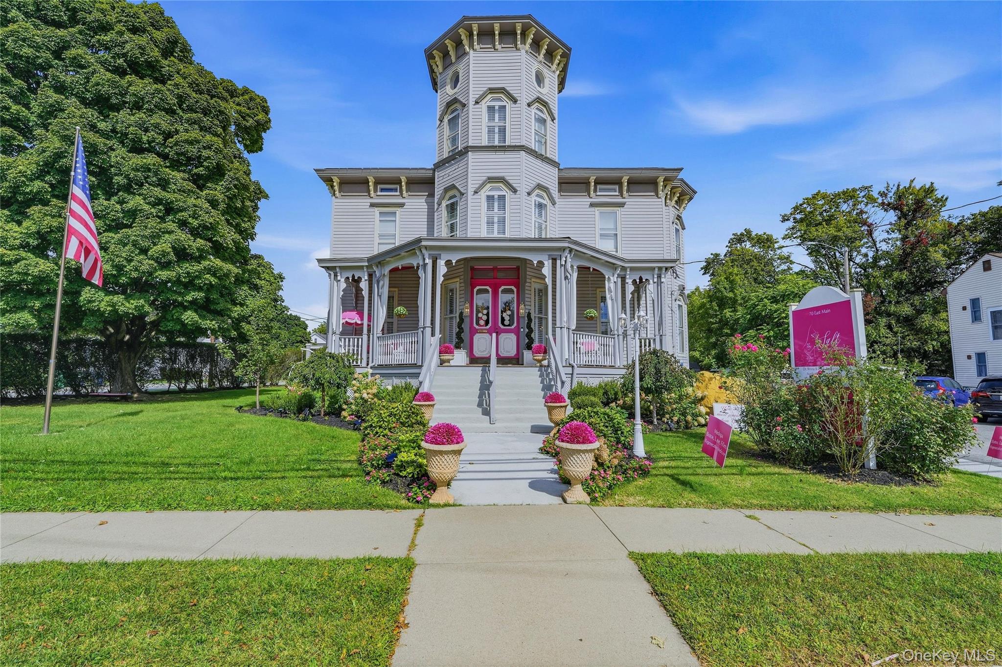 Striking Second Empire architecture showcasing a cylindrical tower with decorative molding, wraparound porch with ornamental railings, and arched entryway