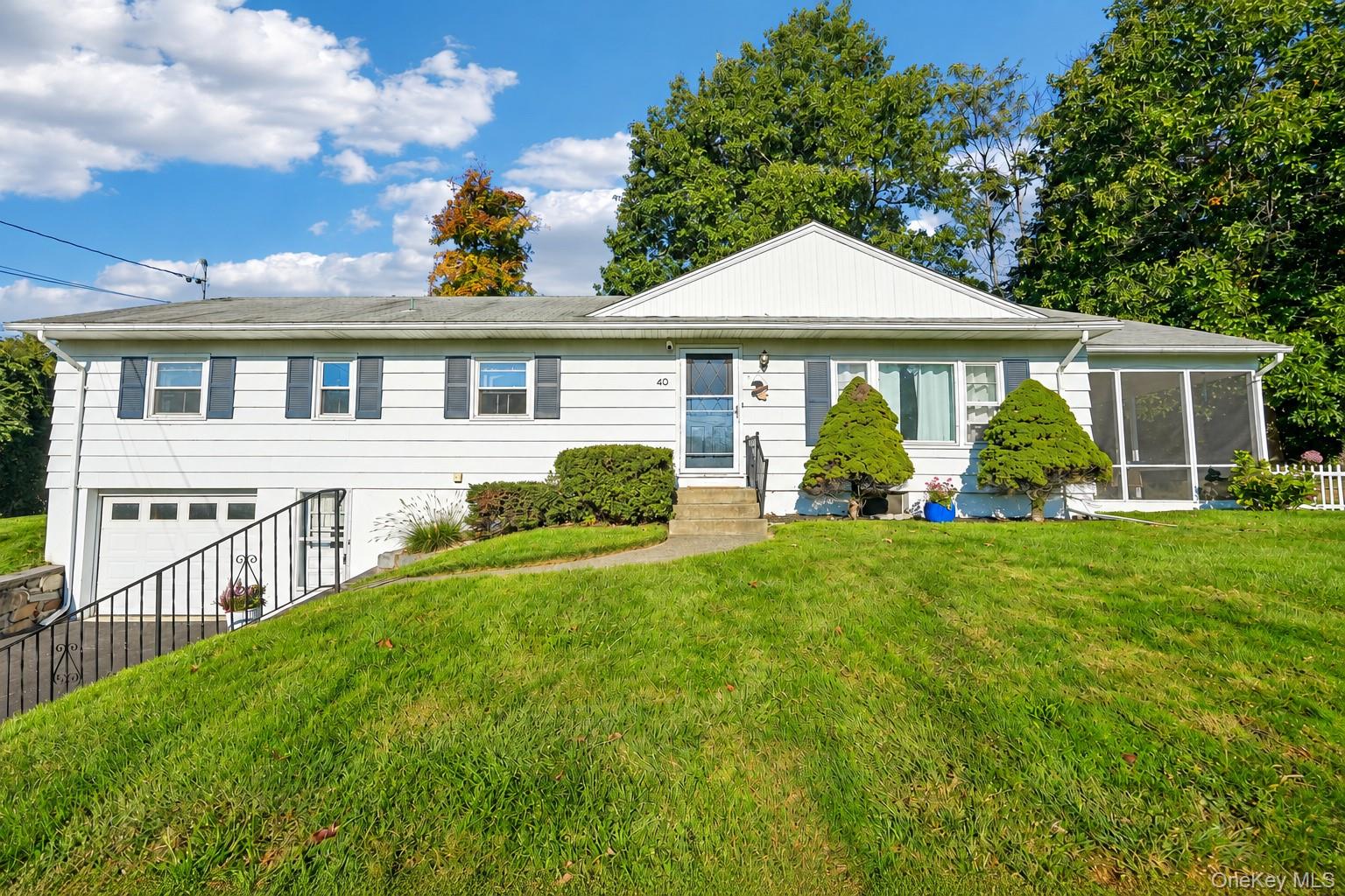 Exterior facade featuring white siding, dark shutters, an integrated garage, and a screened-in porch. Some listing photos have been digitally enhanced or edited for presentation purposes.