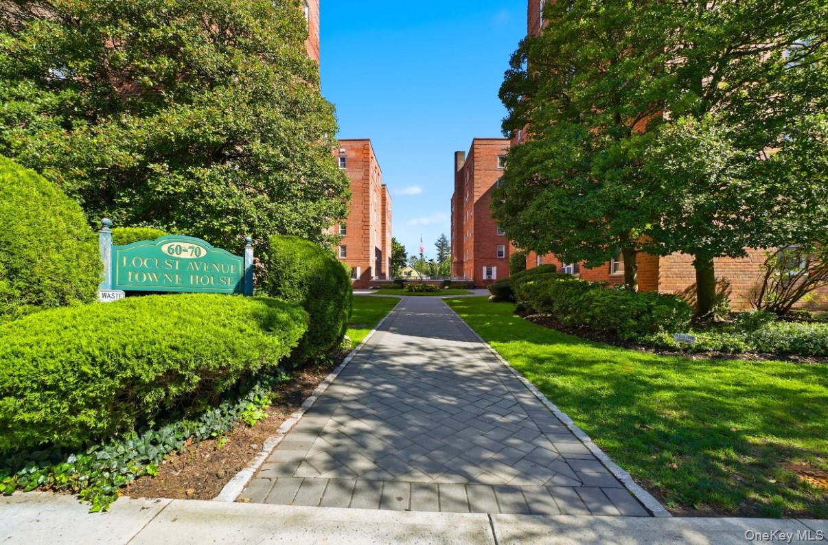 Brick exterior buildings featuring a herringbone-pattern stone walkway, mature landscaping, and manicured lawns